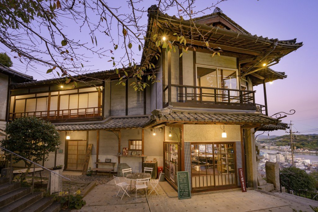 A two-story wooden building lit up at dusk