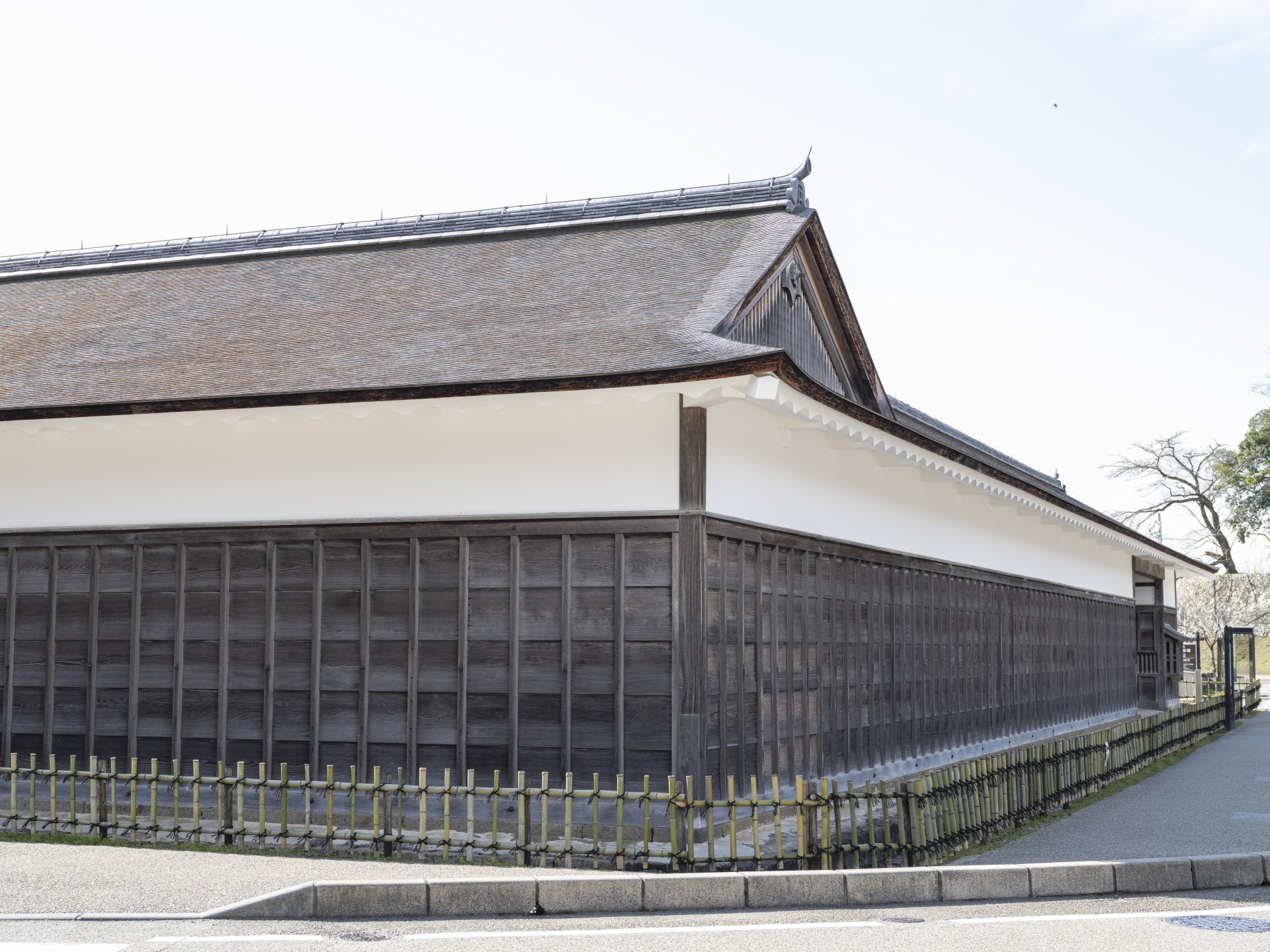 L字に折れて延びる、白壁と板張りの長い馬屋