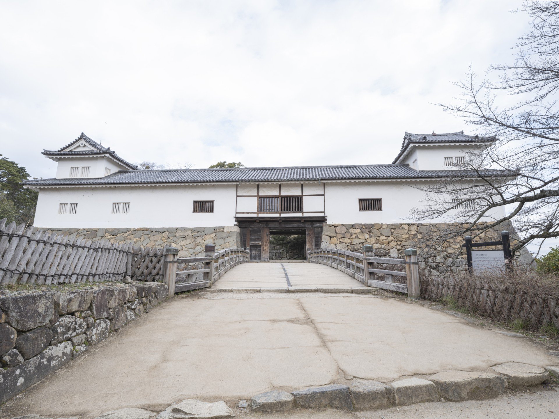 廊下橋の先に建つ白壁の天秤櫓。中央に門、左右に二重の隅櫓