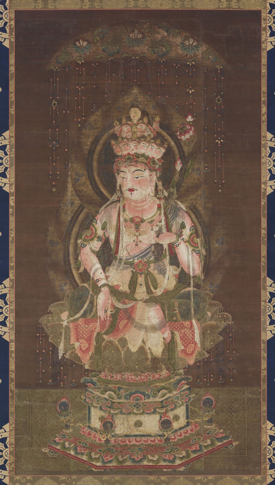 The Eleven-Headed Kannon wearing a jeweled crown, seated on a lotus pedestal