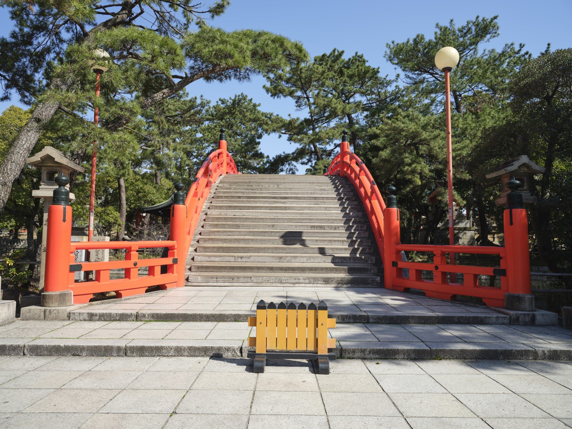 The vermilion arched bridge seen between stone lanterns